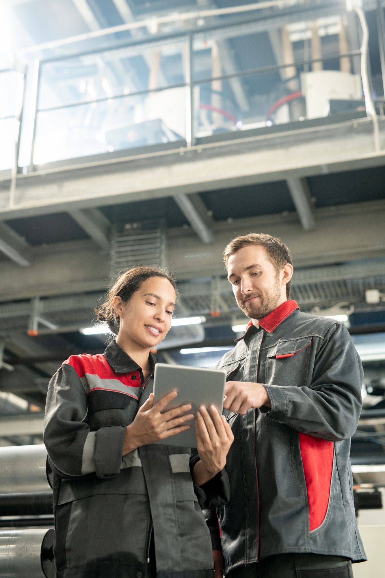 Young quality control managers of contemporary factory scrolling through data